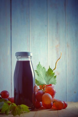 Grape juice in glass bottle, organic fresh grapes on background, The best of drink for healthy and holiday celebration ideas concept, free space for text. Vintage toned image.の写真素材