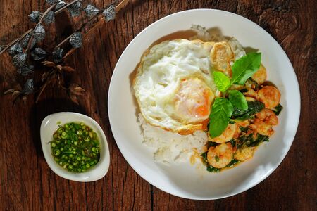 Thai food : Kaphrao Kung is Stirred and fried shrimps with holy basil and chilies served on steamed rice and fried egg. Shooting in studio for advertising. Thai and Asian food concept.の写真素材