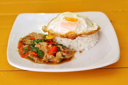 Thai food : Kaphrao Moo is Stirred and fried pork with holy basil and chilies served on steamed rice and fried egg. Shooting in studio for advertising. Thai and Asian food concept.の写真素材