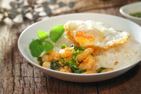 Thai food : Kaphrao Kung is Stirred and fried shrimps with holy basil and chilies served on steamed rice and fried egg. Shooting in studio for advertising. Thai and Asian food concept.の写真素材