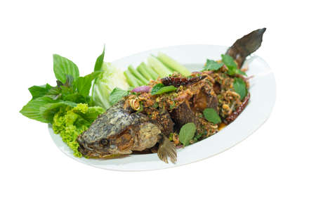 Larb plachon is fried snake-head fish topping with chili and spicy herbs. Served with vegetable,sticky rice. Spicy fried fish salad on white dish isolated on white background with path.