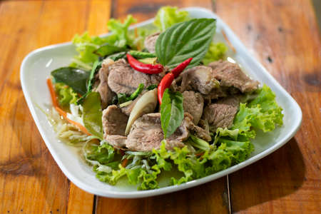 A dish of steamed beef served with vegetable isolated on wooden background.の写真素材