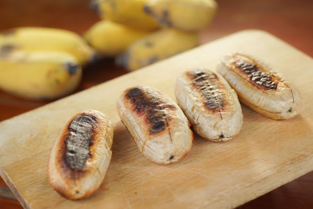 Banana Roasted. Grilled bananas on wooden chop. Selective focus. Vegan food, vegetarian tropical food.の写真素材