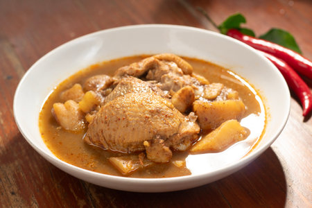 Chicken curry in white bowl on wooden table background, Thai food.の写真素材