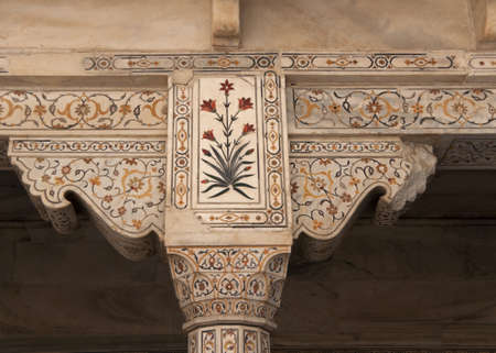 Beautiful marble lay-in work of flowers on pillar top and support at Agra Fort Palace in India. Yellows, reds and dark greens against beige marble surfaces.のeditorial素材