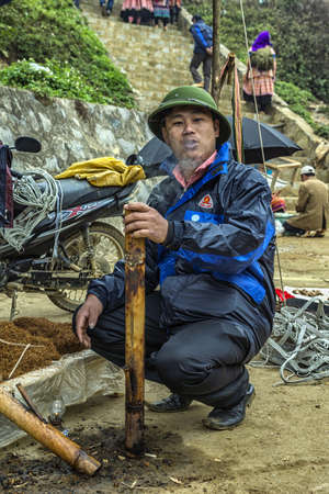 Man smoking tobacco in large pipe on Sunday market. Test before you buy.のeditorial素材