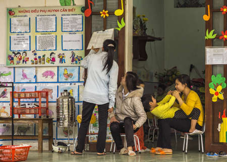 Three teachers check schedule against decor of children's drawings.のeditorial素材