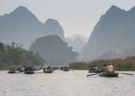 Vietnam Ninh Binh - March 14, 2012: rowing tourists on lakes between limestone mountains.のeditorial素材