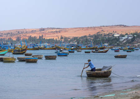 Vietnam - March 2012: Man rows supplies to the fishing fleet anchored in front of the coast.のeditorial素材