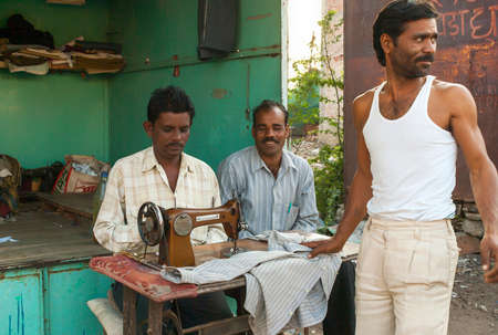 KHAJURAHO, INDIA - CIRCA FEBRUARY 2011  Tailor working his sewing machine in front of small street booth のeditorial素材