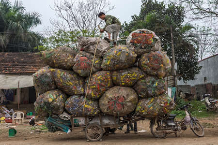 HANOI, VIETNAM - CIRCA MARCH 2012: Recycling cans and bottles loaded on cart behind motorbike....