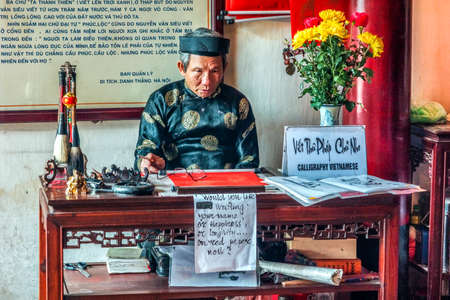 HANOI, VIETNAM - CIRCA MARCH 2012: Old man offers calligraphy in Ngoc Son temple. Staring as if he...