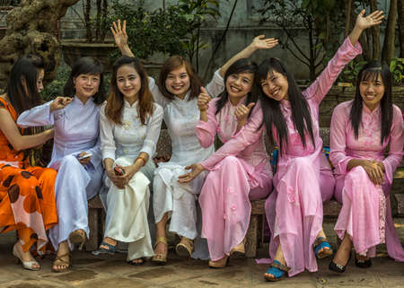 HANOI, VIETNAM - CIRCA MARCH 2012: Seven joyful female university seniors dressed in Ao Dai. Happy smiles and positive waves at Temple of Literature.のeditorial素材