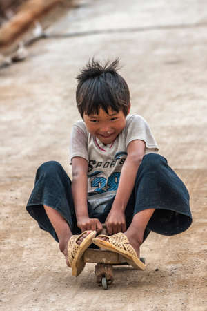 LAO CHAI, VIETNAM - CIRCA MARCH 2012: Kid on three wheeled skate board coming down hill. Flying...