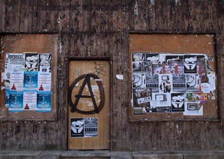 PLZEN, CZECH REPUBLIC - CIRCA SEPTEMBER 2010  A business with dark filthy wooden walls is completely boarded up  Anarchist have painted their classic encircled A-logo on the door, and have glued anti-capitalist posters near by  Capitatlism is written in tのeditorial素材