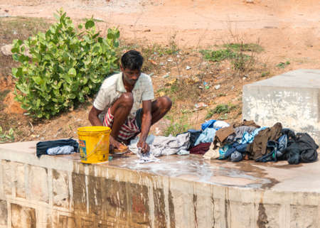 India Khajuraho - 24 February 2011 - Man doing laundry manually on the concrete slab of river bridge のeditorial素材