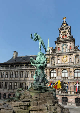 Statue of the Roman warrior Brabo who throws the hand of the giant Antigoon in the Scheldt River, says the legend  Background is the historic city hall  Antwerpen, hand werpen  Dutch , throw hand のeditorial素材