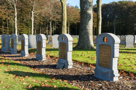 HOUTHULST, BELGIUM - OCTOBER 27, 2014: First tombstone for Unknown Soldier. Lines of tombstones under trees covered in fall colors for the soldiers who fell during the last major attack of the war against the Germans.のeditorial素材