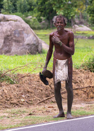 KUMBAKONAM, INDIA - OCTOBER 10, 2013: A dark-skinned Tamil man walks along the road wearing just a...