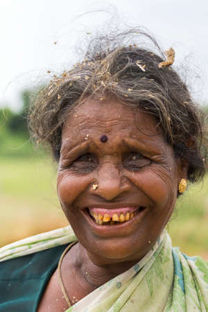 KUMBAKONAM, INDIA - OCTOBER 10, 2013: Close-up of older woman farmer with bad teeth and millet husks in her graying hair.のeditorial素材