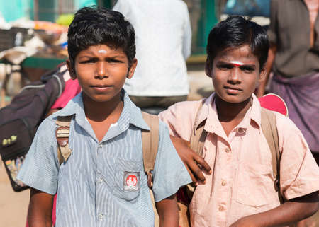 KUMBAKONAM, INDIA - OCTOBER 11, 2013: Two young Hindu schoolboys look into the camera. Their black...