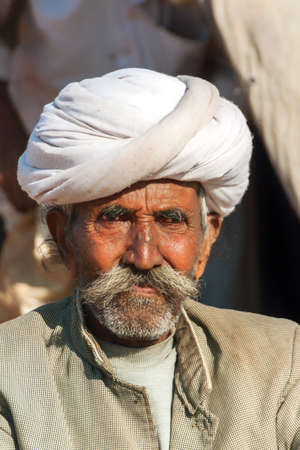 NAGAUR, INDIA - FEBRUARY 10, 2011: An old cattle farmer with white turban looks into the camera. Heのeditorial素材