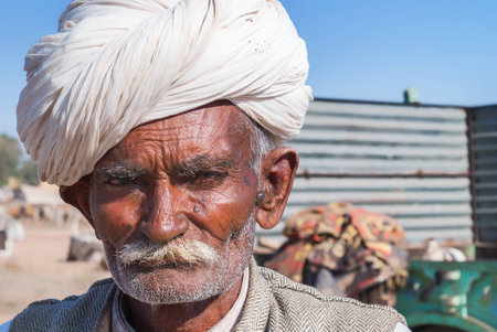 NAGAUR, INDIA - FEBRUARY 10, 2011: A stern old cattle farmer with white turban looks into the camera. Heのeditorial素材