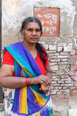 BITHOOR, INDIA - MARCH 2, 2011: This graying woman, dressed in a colorful blue, yellow sari over a...