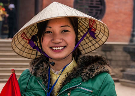 Chua Bai Dinh Pagoda, Vietnam - March 14, 2012: Closeup of young Vietnamese Woman with traditional straw hat.のeditorial素材