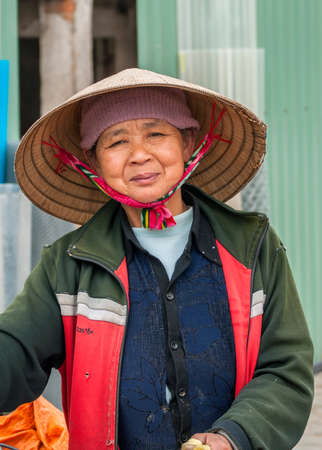 VINH, VIETNAM - MARCH 15, 2012: Closeup of middle-aged Vietnamese woman with traditional straw hat.のeditorial素材