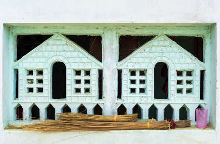KUMBAKONAM, INDIA - OCTOBER 11, 2013: A stone decoration is built into a window opening of a poor dwelling to create a sense of privacy for those inside. Its hard to look inside. Handmade small brooms lie on the ledge.のeditorial素材