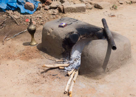 KUMBAKONAM, INDIA - OCTOBER 11, 2013: Mud kitchen stove in village outside home. Remnants of firewood, ashes and matches. The pot will be set on top of the round opening.のeditorial素材