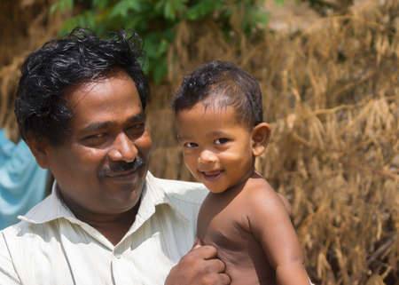 KUMBAKONAM, INDIA - OCTOBER 11, 2013: Proud father shows his baby son sitting on dadâs arm.のeditorial素材