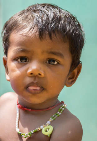 KUMBAKONAM, INDIA - OCTOBER 11, 2013: Closeup of Tamil baby girl's face. She extend her little tongue a bit, looks serious, while the photographer is mirrored in her eyes.のeditorial素材