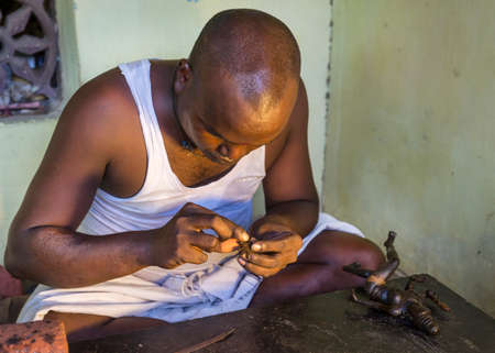 KUMBAKONAM, INDIA - OCTOBER 11, 2013: A male artist creates with his hands and a few rudimentary tools the model of a statue in beeswax. Scene at artisanal metal foundry.のeditorial素材