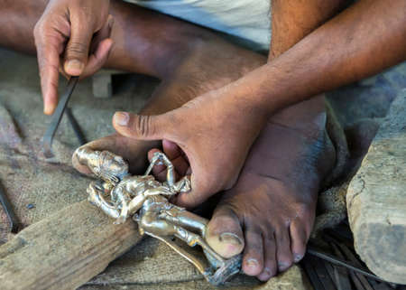 KUMBAKONAM, INDIA - OCTOBER 11, 2013: Closeup of hands cleaning the metal statue that came out of the clay mold. Tiny pieces of clay must be removed out of crevices and nooks.のeditorial素材