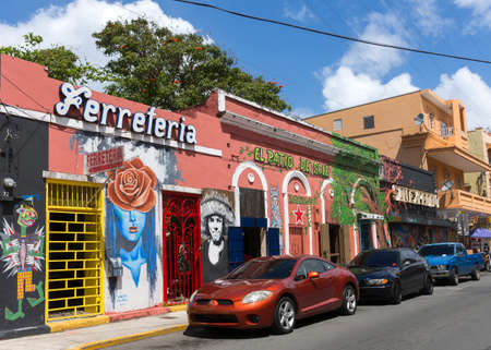 SAN JUAN, PUERTO RICO - MARCH 13, 2015: Facades of bars and restaurants in Calle Elisa Colberg in the Tras Talleres neighborhood. Parked cars, wall paintings and graffiti. Blue sky with white clouds.のeditorial素材