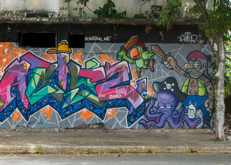 SAN JUAN, PUERTO RICO - MARCH 13, 2015: Graffiti in Tras Talleres neighborhood. Very sharp image of a group of cartoonish pirates, including parot and octopus. All seem to in attack mode. Bright colors against gray wall with tree in the picture.のeditorial素材