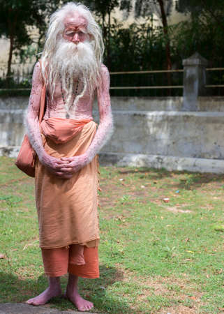 KUMBAKONAM, INDIA - OCTOBER 12, 2013: Old, half-blind, albino Sadhu wanders around the Mahalingeswarar Temple as a daily spiritual routine.のeditorial素材