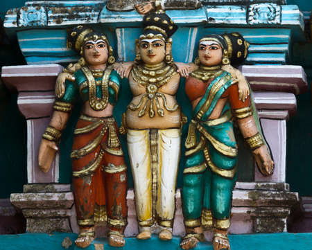 KUMBAKONAM, INDIA - OCTOBER 12, 2013: Mahalingeswarar Temple. Wear and tear have damaged the lesser Gopurams. Cute trio statue of a male and two females on top of said Gopurams. Black mold affected the pastel colors.のeditorial素材