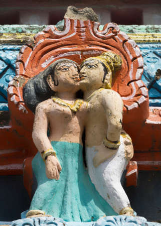 KUMBAKONAM, INDIA - OCTOBER 12, 2013: Mahalingeswarar Temple. Wear and tear have damaged the lesser Gopurams. Cute statue of standing, half-naked, kissing couple.  Black mold affected the pastel colors.のeditorial素材