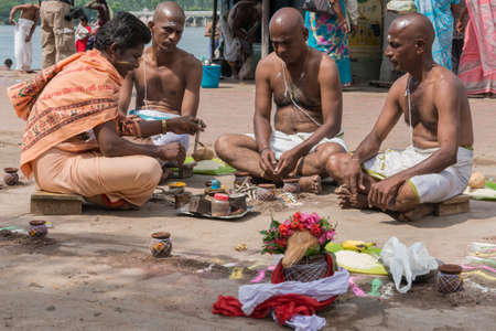 Trichy, India - October 15, 2013: Sitting in a mandala, three brothers mourn their mother under the guidance of guru at Amma Mandapam.のeditorial素材