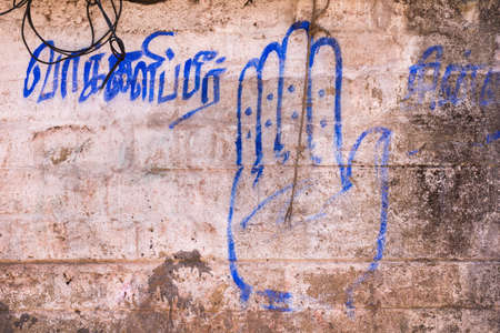 Chettinad, India - October 16, 2013: The blue hand symbol of India National Congress Party is painted on a beige, brown wall with words in Tamil.のeditorial素材