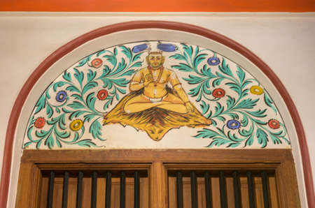 Chettinad, India - October 17, 2013: Chidambara Palace in Kadiapatti. Wall painting above door showing Thayumanavar, famous Tamil guru and saint. Sitting among flowers.のeditorial素材