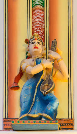 Chettinad, India - October 17, 2013: Chidambara Palace in Kadiapatti. Statue of Veena playing topless woman with blue sari in dance hall. Multi colored warm background.のeditorial素材