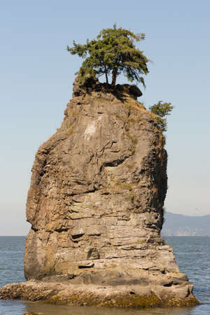 Vancouver, Canada - July 24, 2016: Portrait of the iconic Siwash Rock which stands in the ocean a few meters off Stanley park. Clear skiesの写真素材