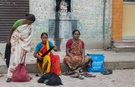 Madurai, India - October 19, 2013: Three women sell black human hair out of bags while sitting on the sidewalk near the Meenakshi Temple. All wear saris.のeditorial素材