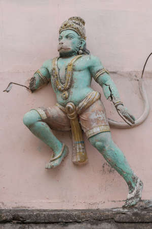 Severely damaged and neglected green Lord Hanuman statue against pink wall. Near Meenakshi Temple. He seems to jump forward.の写真素材