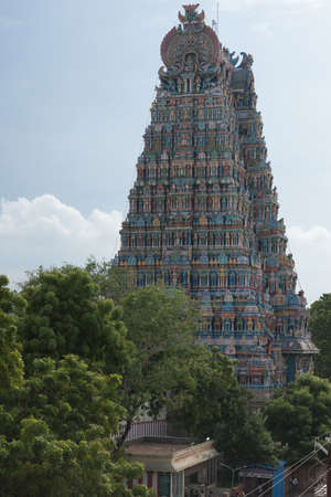 Madurai, India - October 19, 2013: Closeup of the North Gopuram of the Meenakshi Temple against faint blue sky. Seen from the West. Bottom behind green trees.の写真素材