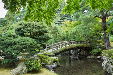Kyoto, Japan - September 14, 2016: Part of the Japanese garden at the Imperial palace showing bow bridge, pond, and multiple trees.のeditorial素材